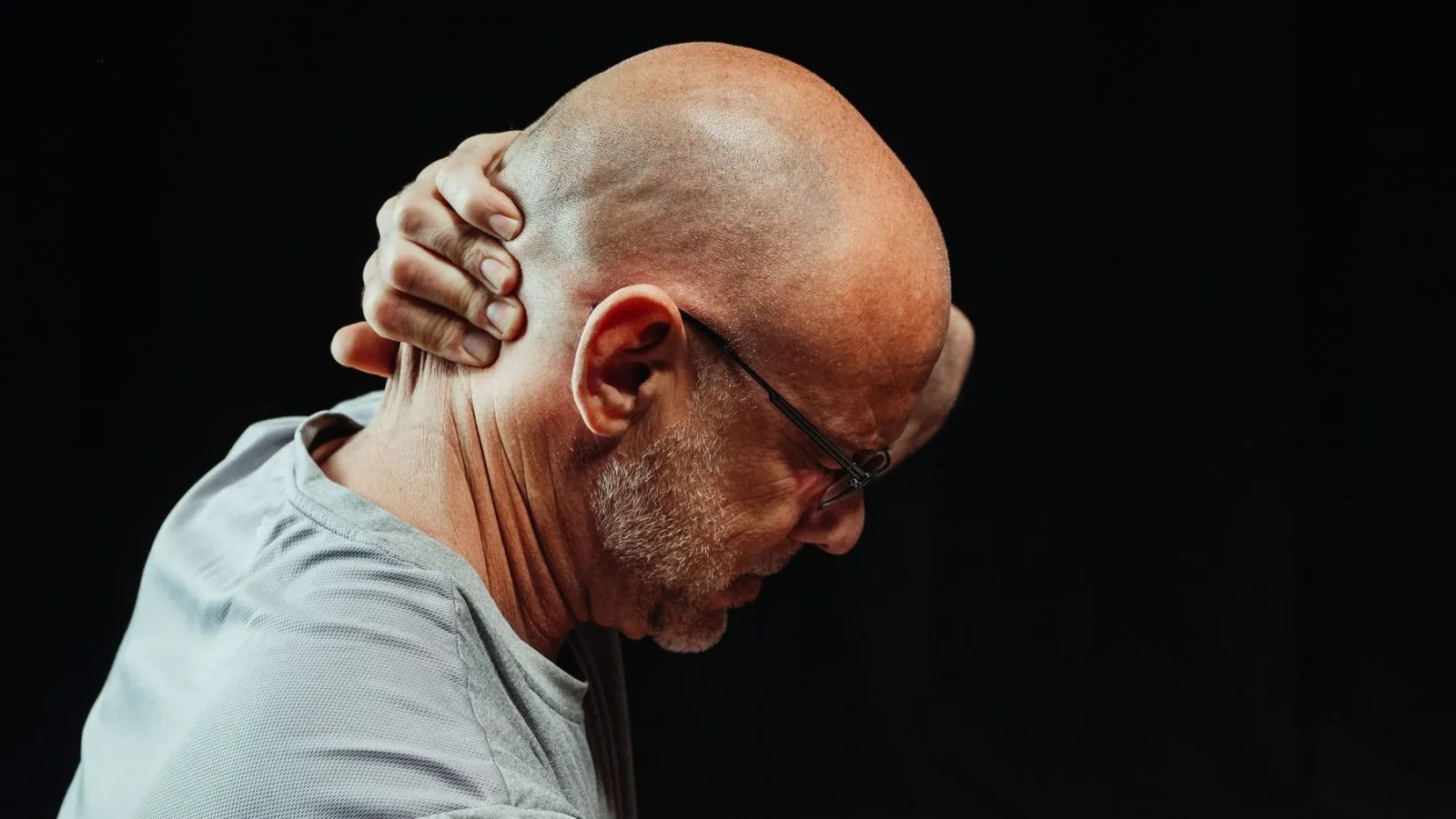 Boyun fıtığı belirtilerinden boyun ağrısıyla ensesini tutan adam